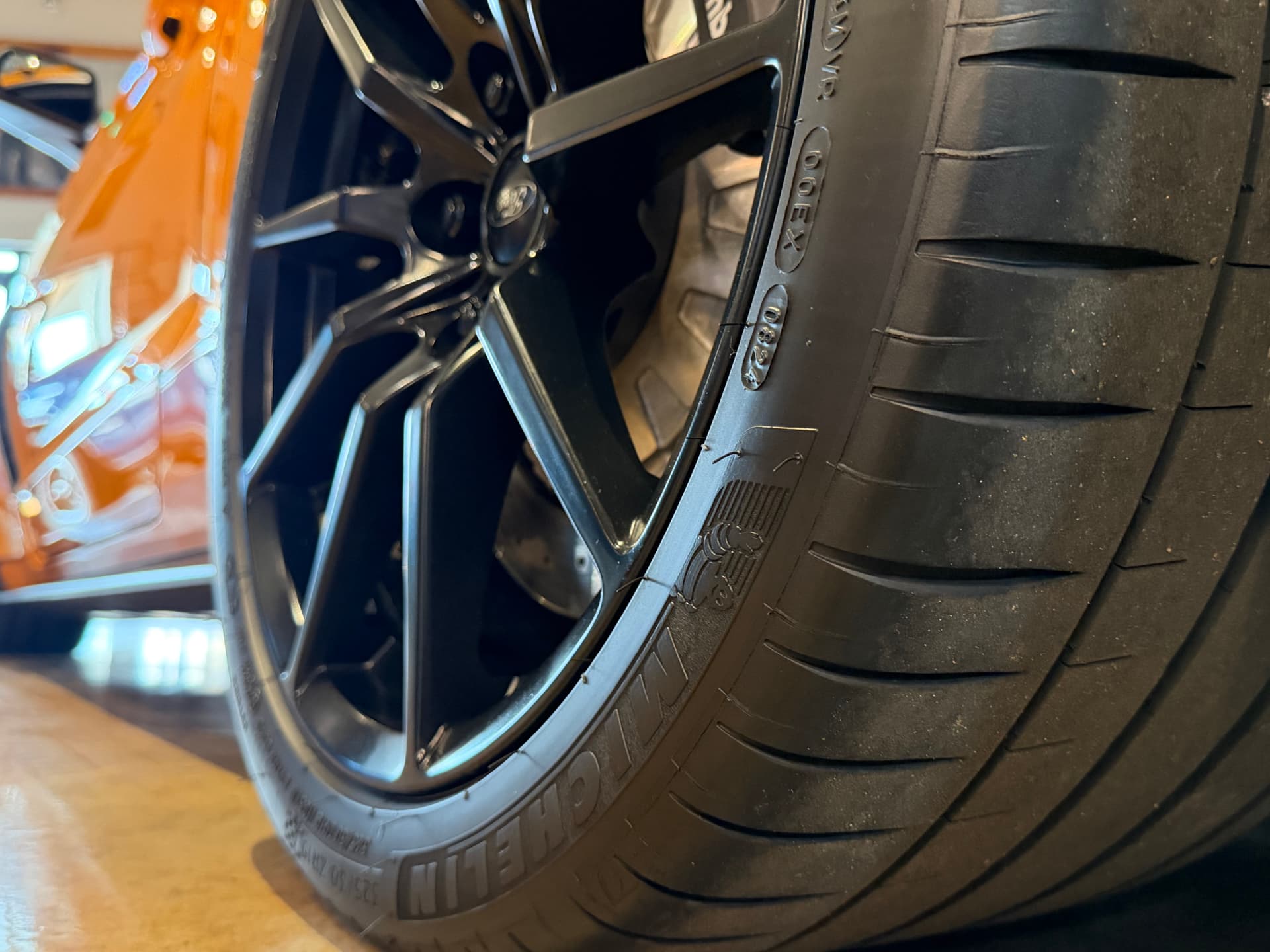 Close-up of a Michelin performance tire and black alloy wheel on a car inside the Restoration Rods showroom.