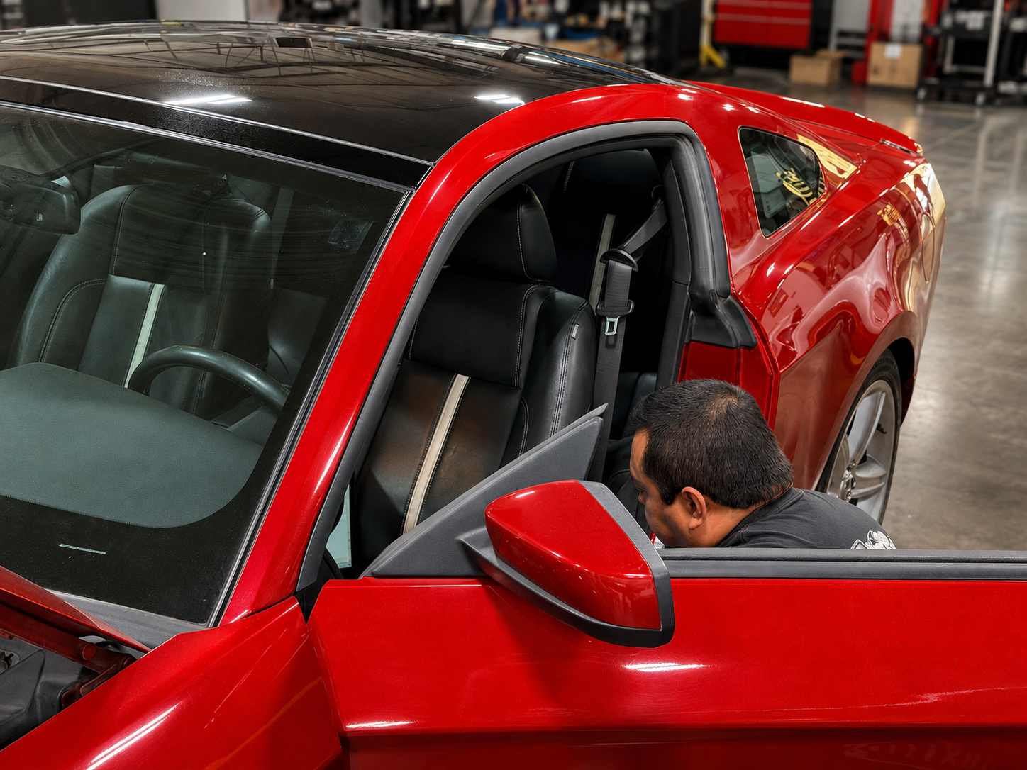 Technician inspecting a red Chevrolet Camaro with the door open in the Restoration Rods shop